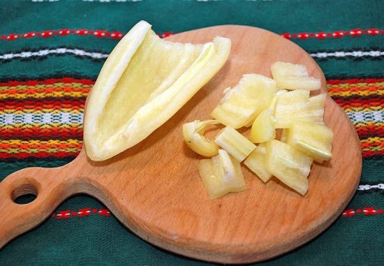 Нарезанный кусочками сладкий перец на деревянной разделочной доске